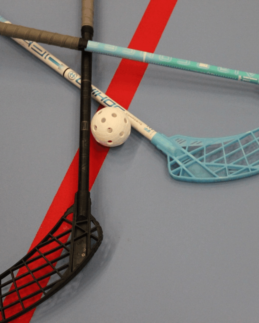 jolly-sticks je ziet unihockey sticks op de gymzaalvloer liggen met een bal