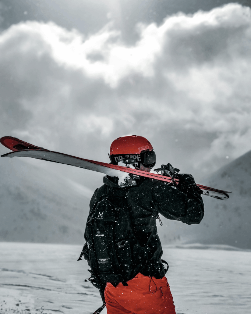 je ziet een skier in de sneeuw met zn skies op zn schouders