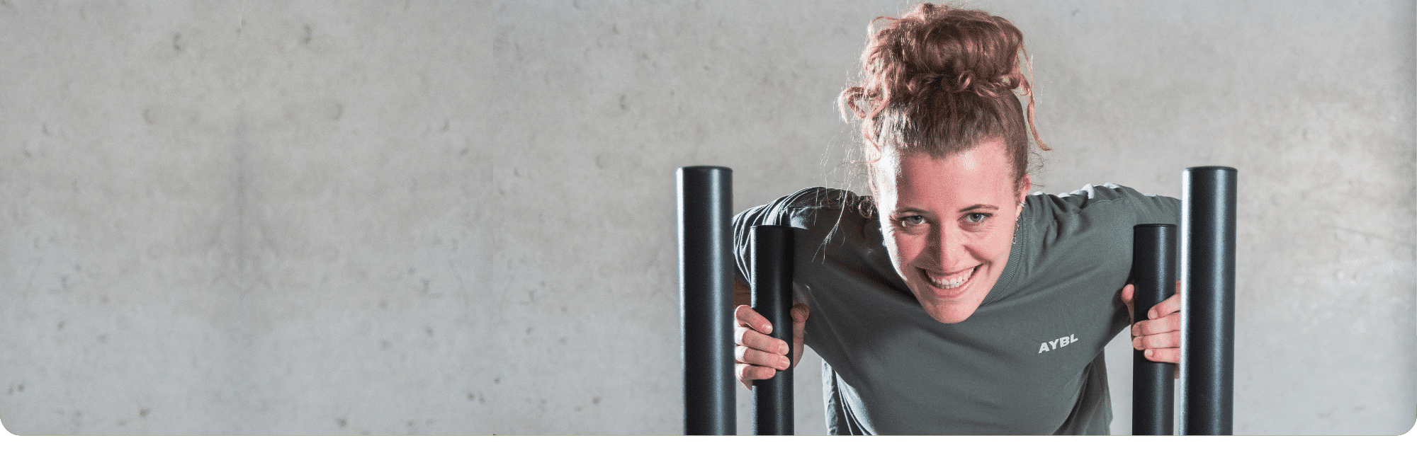 gewichtensled-sportschool-contact Vrouw glimlacht terwijl ze een gewichtensled duwt in de sportschool